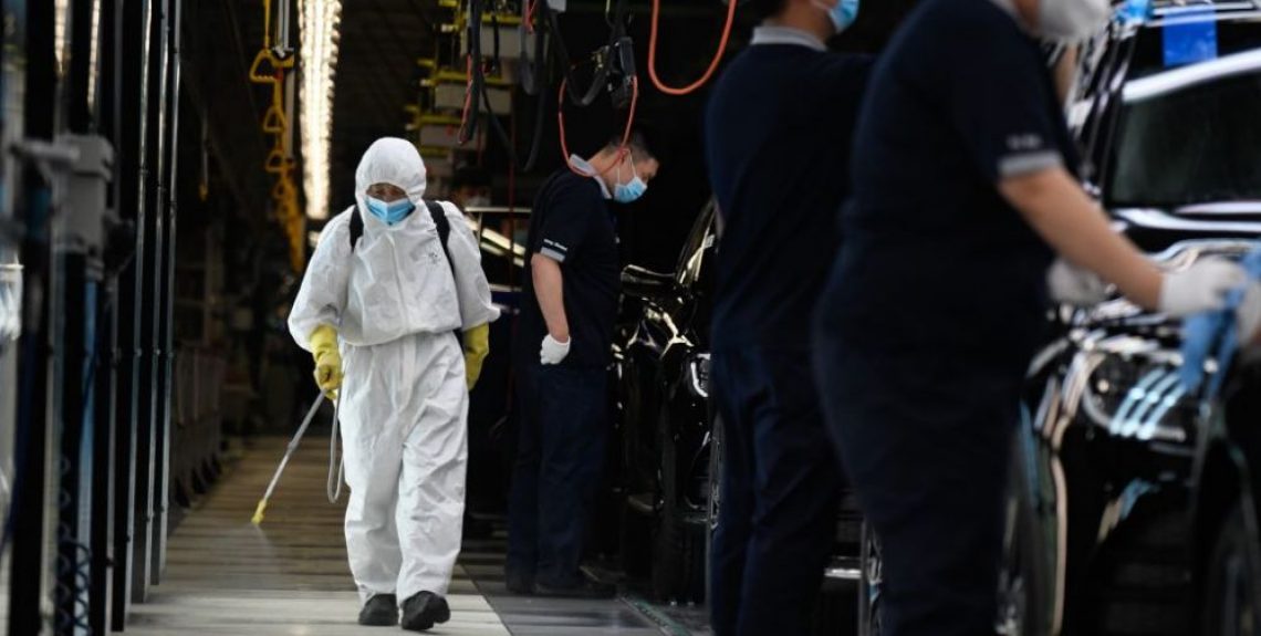 A cleaner wearing protective gear sprays disinfectant along a production line at a Mercedes Benz automotive plant during a media tour organised by the government in Beijing on May 13, 2020, as the country's industrial sector starts again following shutdowns during the COVID-19 coronavirus outbreak. (Photo by WANG Zhao / AFP) (Photo by WANG ZHAO/AFP via Getty Images)